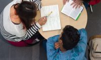 An up angle photo of three people studying at a round table